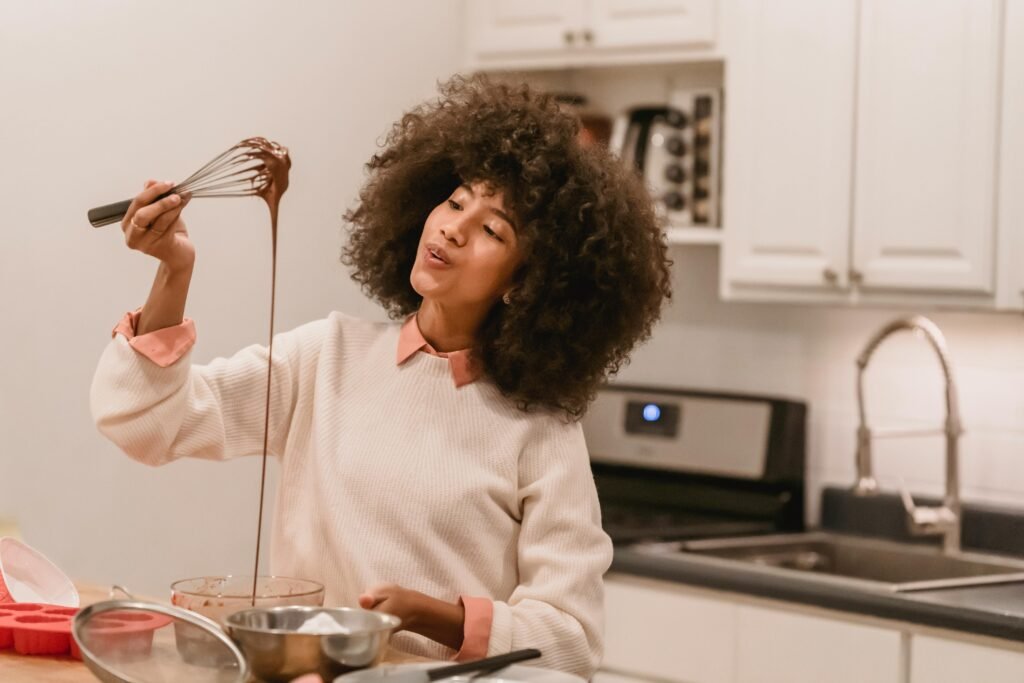 A cheerful woman enjoying baking chocolate dessert in her home kitchen.